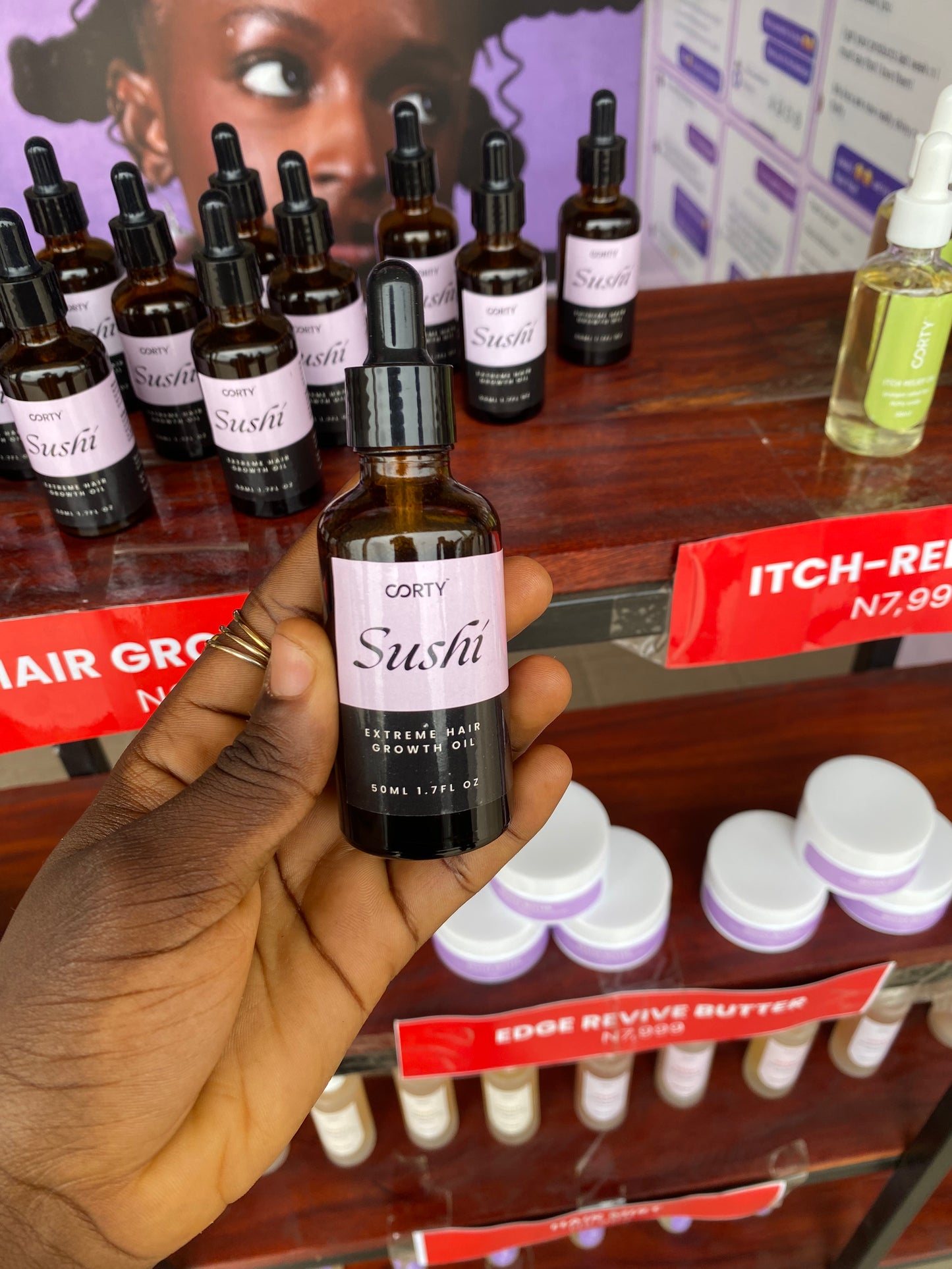 Hand holding a bottle labeled 'Sushi' with various other bottles and products in the background.